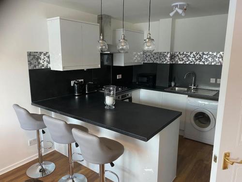 a kitchen with a black counter and two bar stools at Perfectly situated luxury 2 bedroom apartment in Glasgow