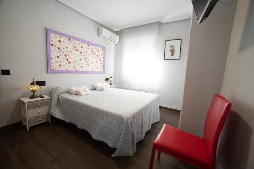 1 dormitorio con 1 cama y 1 silla roja en DEL ARZOBISPO, en Plasencia