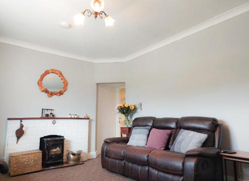 a living room with a leather couch and a fireplace at Farm View Cottage Castlerea by Trident Holiday Homes in Castlerea