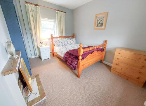 a bedroom with a wooden bed and a window at Farm View Cottage Castlerea in Castlerea