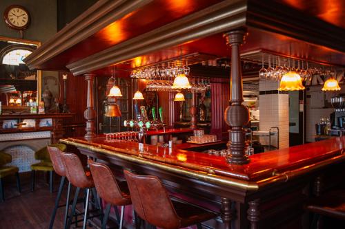 a bar with chairs and a counter in a room at De Zon Hotel & Restaurant by Flow in Ommen