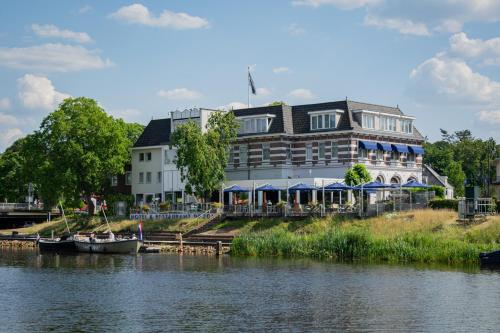 a large building next to a river with a boat at Hotel de Zon - Brasserie Bresson by Flow in Ommen
