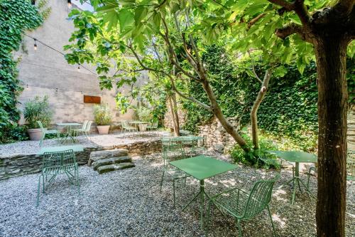 a patio with tables and chairs under a tree at Au Ralenti du Lierre in Beaumettes