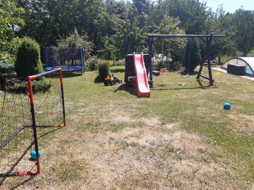 a playground with a slide and a swing set at Apartmány Roudnice in Jestrabi V Krkonosich