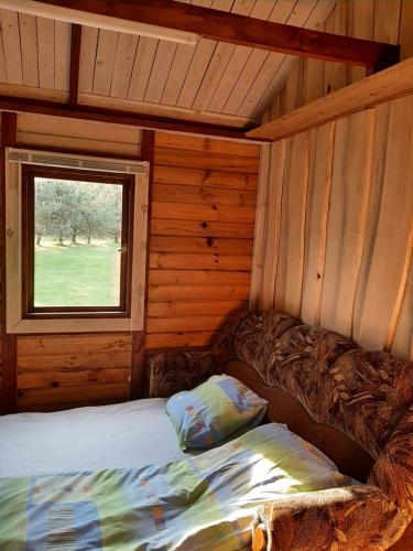 uma cama num chalé de madeira com uma janela em Mėgstantiems gaminti gamtoje 