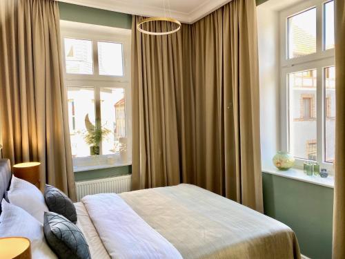a bedroom with a bed and two windows at Apartament Morska 5-4 in Darłowo