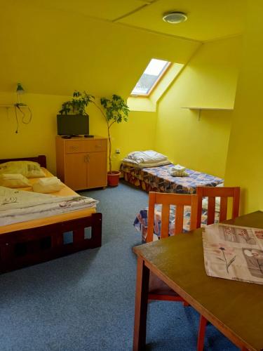 a room with two beds and a table and chairs at Penzion Lukáš in Malá Morávka