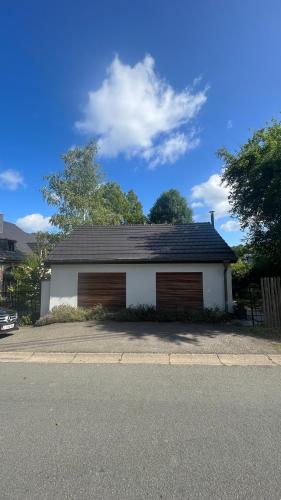 a white house with two garage doors on a street at L'Atelier in Spa
