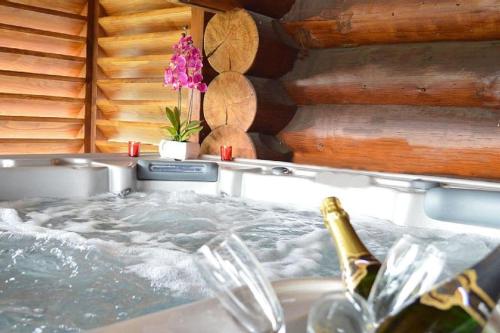 Cette chambre comprend une baignoire et une bouteille de champagne. dans l'établissement Chalet SPA Le Royal Nathalie MN La rouge, à La Bresse