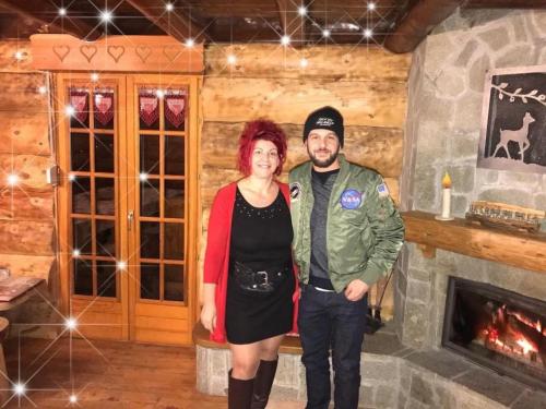 un homme et une femme debout dans une pièce avec une cheminée dans l'établissement Chalet SPA Le Royal Nathalie MN La rouge, à La Bresse