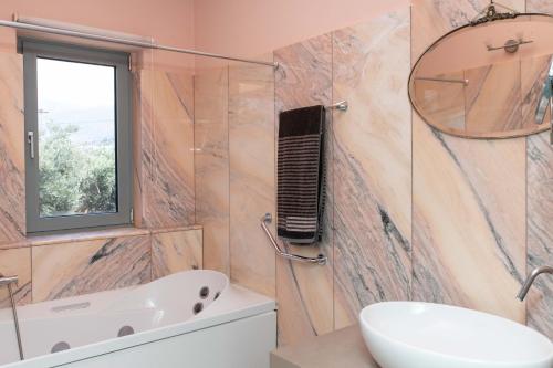 a bathroom with a tub and a sink and a mirror at Kastelokampos Art House in Patra