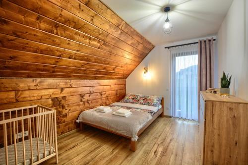 a bedroom with a wooden accent wall and a bed at Chaty na Skalistym Wzgórzu in Solina