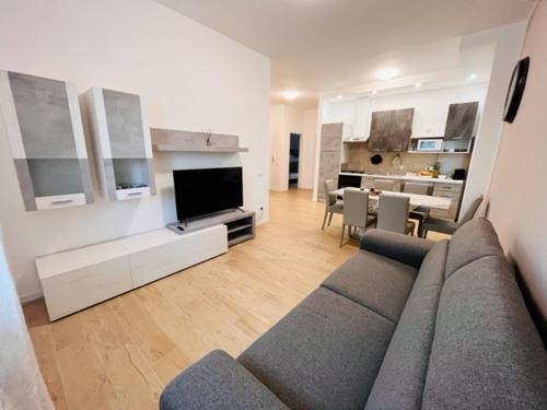 een woonkamer met een bank en een tv en een keuken bij IL DANDY appartamento con parcheggio in Trieste