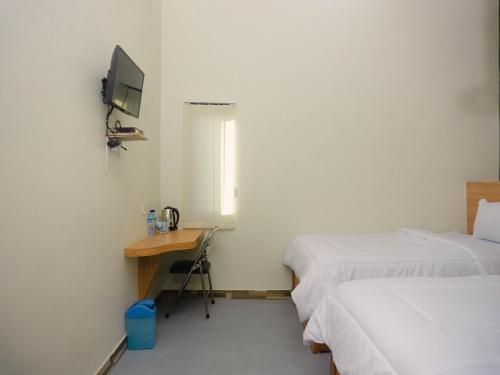 a room with two beds and a desk and a television at GRAND KHALIFAH Guesthouse in Sumbawa Besar