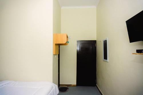 a bedroom with a bed and a black door at GRAND KHALIFAH Guesthouse in Sumbawa Besar
