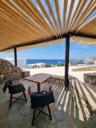 a patio with a table and chairs under a wooden roof at Seethrough Mykonos Suites in Platis Yialos Mykonos