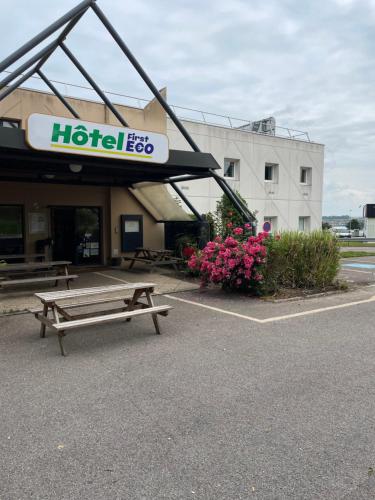 a hotel with a bench in front of a building at Hotel First Eco Dieppe in Dieppe