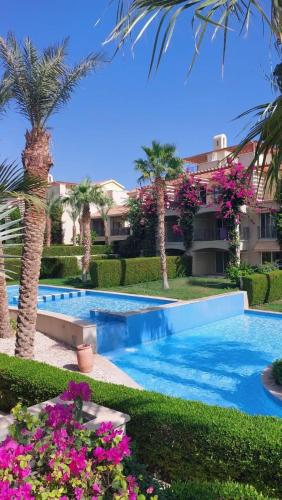 a resort swimming pool with palm trees and flowers at veranda sahl hasheesh in Hurghada