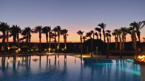 a large swimming pool with palm trees at dusk at veranda sahl hasheesh in Hurghada