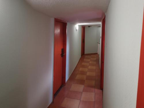 an empty hallway with a red door and a tile floor at Jáde Panzió in Budapest