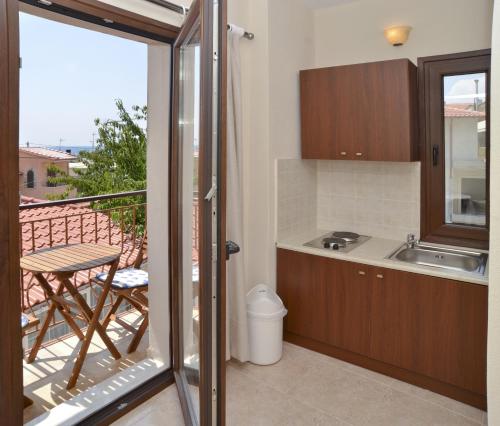 eine Küche mit einem Balkon mit einem Tisch und einem Waschbecken in der Unterkunft VILLA ELENI in Skala Marion