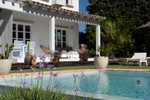 une maison avec une piscine et des fleurs violettes dans l'établissement Casa La Siesta, à Vejer de la Frontera