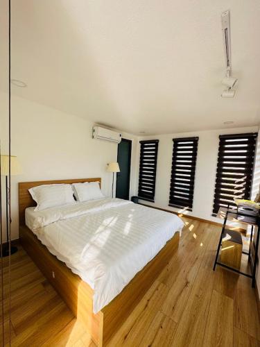 a bedroom with a large bed with white sheets and windows at Sol Valley - Hideaway Station in Blao Srê