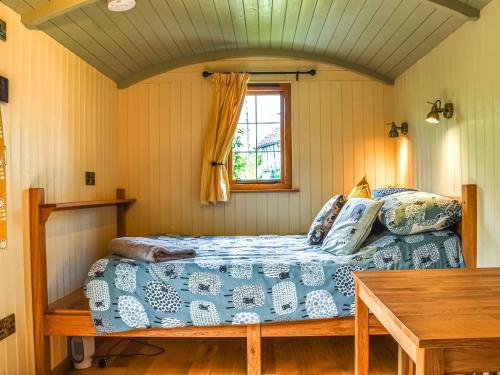 a bedroom with a bed and a window and a table at Bechan Brook Hut in Bettws Cedewain