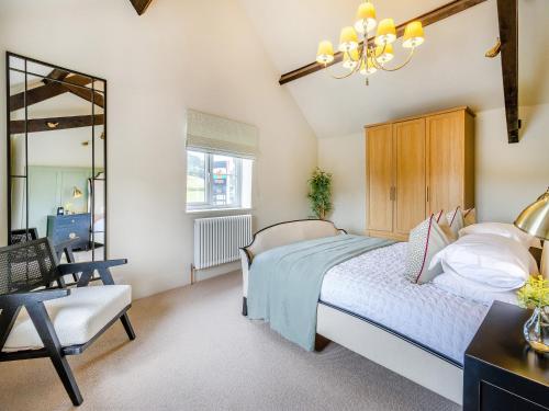 a bedroom with a bed and a chair and a chandelier at Dant Y Llew - Uk42790 in Bow Street