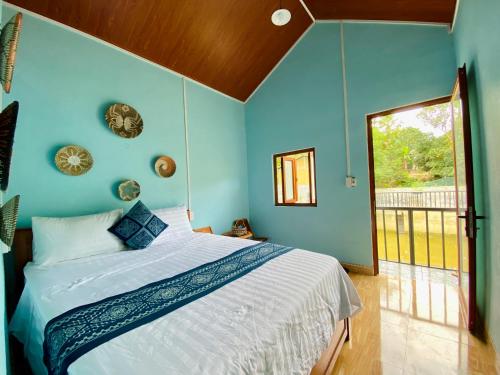 Un dormitorio con una cama con paredes azules y una ventana en Tay Farmhouse en Ha Giang