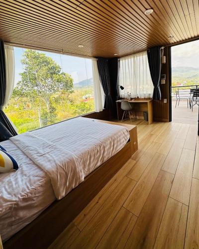 a bedroom with a large bed and a large window at Sol Valley - Hideaway Station in Blao Srê