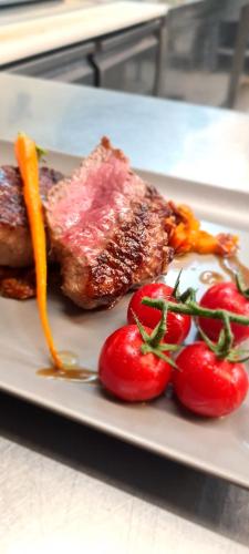 a plate of food with meat and tomatoes on a table at Hotel & Restaurant Zum Deutschen Hause in Kirchhatten