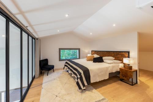 una camera da letto con un letto e una sedia di Villa de luxe au Pyla avec piscine en bordure du golf d'Arcachon, 5 chambres a La Teste-de-Buch
