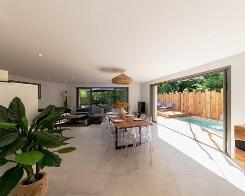 una sala da pranzo con tavolo e piscina di Villa de luxe au Pyla avec piscine en bordure du golf d'Arcachon, 5 chambres a La Teste-de-Buch