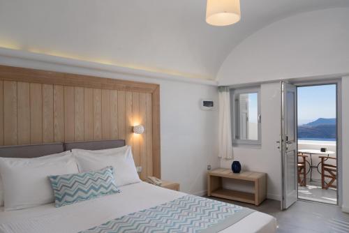 a bedroom with a bed and a balcony with a table at Volcano View by Caldera Collection in Fira