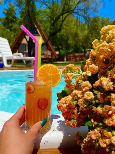 a person holding a glass of orange juice next to a pool at BADEM AĞACI BUGALOWLARI in Kas