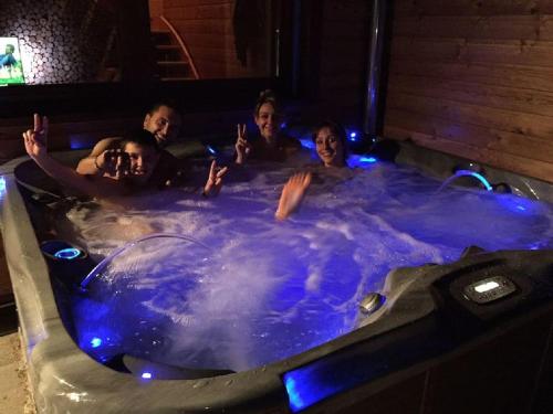 Un groupe de personnes dans un jacuzzi dans l'établissement Chalet SPA Le Coin De Paradis Nathalie MN La rouge, à La Bresse