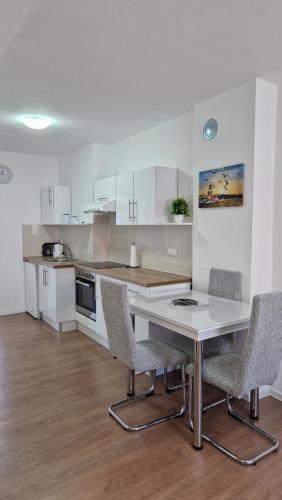 eine Küche mit weißen Schränken sowie einem Tisch und Stühlen in der Unterkunft Apartmani SKY 1 2 3 in Brčko