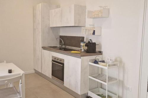 een kleine keuken met witte kasten en een spoelbak bij Piccolo appartamento di charme in Napels