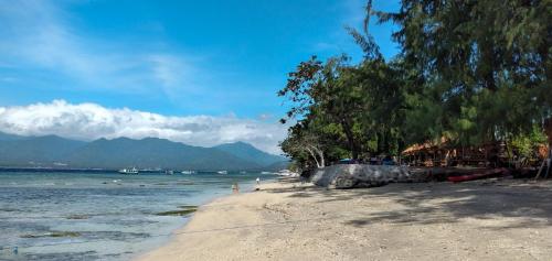 a beach with trees and people swimming in the water at Gili Moonlight Retreat in Gili Air
