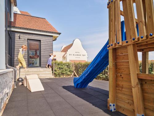 two children playing on a playground with a blue slide at Hotel de Blanke Top in Cadzand-Bad