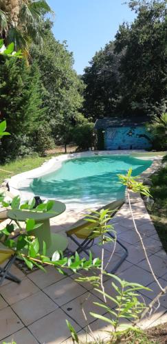 a swimming pool with a table and chairs next to it at Roulotte Fenouillet in Hyères