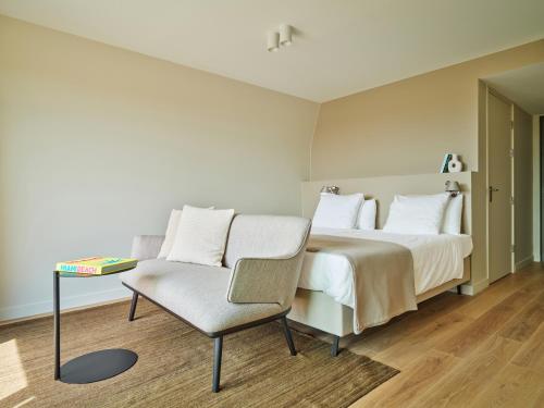 a bedroom with a bed and a chair at Hotel de Blanke Top in Cadzand-Bad
