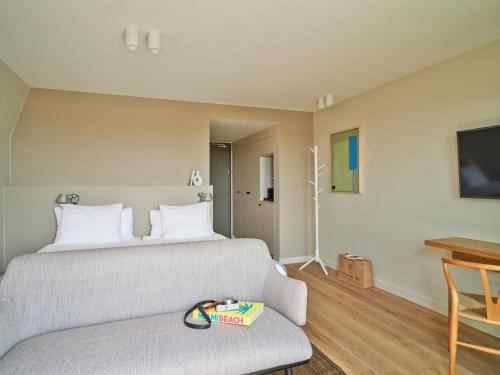 a bedroom with a bed and a couch and a tv at Hotel de Blanke Top in Cadzand-Bad