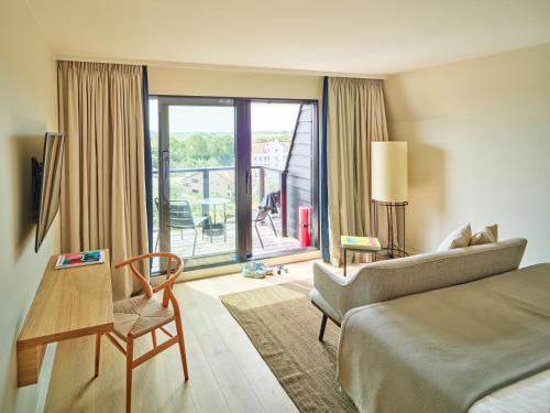 a hotel room with a bed and a balcony at Hotel de Blanke Top in Cadzand-Bad