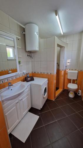 La salle de bains est pourvue d'un lavabo blanc et de toilettes. dans l'établissement Apartman SKY 4, à Brčko