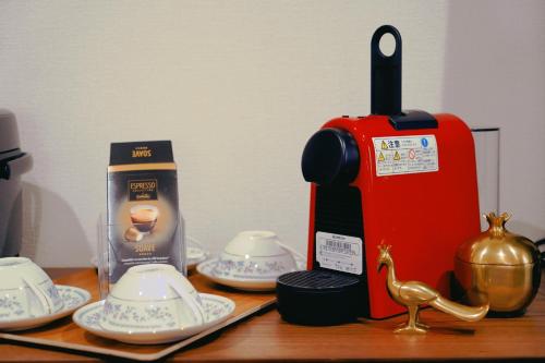 a table with a coffee maker and china on it at Necoana Glamping富士山景BBQトレーラーヴィラ in Fujikawaguchiko