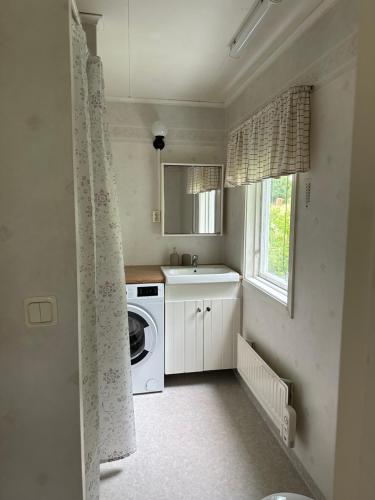 a laundry room with a sink and a washing machine at Björnstugan in Hökerum