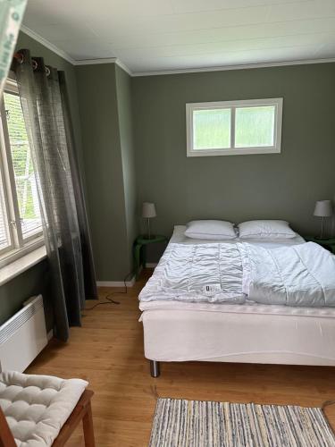 a bedroom with a white bed and two windows at Björnstugan in Hökerum