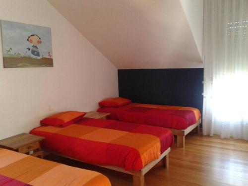 Zimmer mit 3 Betten mit roter und orangefarbener Bettwäsche in der Unterkunft MyHouseSpain -Xivares, Chalet con vistas al mar in Carrió